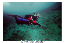 Side-mount diver with helmet cam and lights descending in... by Michael Grebler 